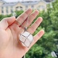 Détail d'un pendentif cage géométrique argenté avec un cristal blanc naturel brut - Cristal blanc