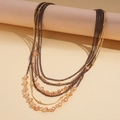 Detail of layered necklace featuring brown chains and amber crystal beads on golden links - Brown