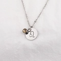 Macro view of Leo zodiac stainless steel necklace with brown birthstone charm on white fabric - Leo Brown Rhinestone (Color No. 5-11)