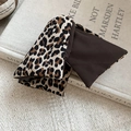 Macro detail of leopard print hair clip showing fabric texture on a book background - Leopard Splicing Dark Brown Style