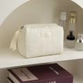 Detail der cremefarbenen gesteppten Kosmetiktasche mit Schleifenstickerei und Seidenband - Cremeweiß Mit Schwarzer Schleife