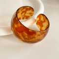 Macro detail of tortoiseshell pattern resin bangle with a chunky C-shaped open design - Amber Tortoiseshell