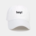 Primo piano dettagliato del ricamo nero 'hey!' su un cappellino da baseball in cotone bianco - Regolabile / Bianco