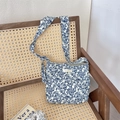Borsa a tracolla in tela floreale blu con etichetta Sorakka su sedia in vimini - Motivo Frutta Blu