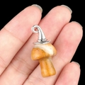 Natural yellow stone mushroom pendant with silver metal cap held by a hand - Gun Black Cap / Crazy Agate