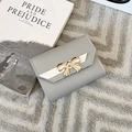Gros plan d'un portefeuille gris en cuir avec nœud doré sur un fond de tapis texturé - Gris