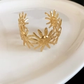 Nahaufnahme eines goldglänzenden Metall-Armreifs mit dekorativen Gesichtern der Sonne - Sonniges Lächeln-Stil (11#)