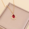 Detail of a red teardrop crystal pendant with small diamonds on a gold chain - Red