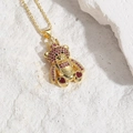 Gold bear pendant necklace featuring red zircon pave and heart-shaped gems on white stone - Rose Red Zirconia