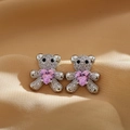 Macro shot of silver bear stud earrings featuring pink heart stones and pavé set crystals - Silver Bear