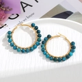 Detailed view of handmade gold wire wrapped earrings with blue stone beads on white tray - Black Blue Beads