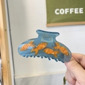 Detailopname van een handgemaakte goudvis haarklem van blauwe hars met oranje visjes - Diepzeevis (9cm)