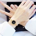 Elegant gold bangle quartz watch with a black dial on a woman's wrist - Arabic Numerals Gold Band Black Dial