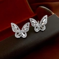 Vue macro de boucles d'oreilles papillon en argent avec zircons brillants sur écrin cuir - Argenté