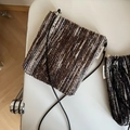 Close-up of woven crossbody mini bag with zip closure and simple wish brand label - Brown