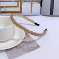 Detailed view of gold braided pearl headband with black anti-slip tips on a white table - Champagne
