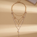 Detail of layered gold necklace with imitation pearls plus star and moon charms - Gold