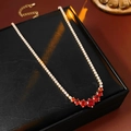 Dettaglio di collana dorata con pietre preziose rosse tonde e accenti di zircone bianco - Oro-Rosso