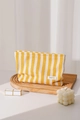 Close-up of yellow striped canvas cosmetic bag with zipper on a wooden tray - Yellow Plaid
