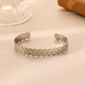 Detail shot of silver stainless steel open cuff bracelet with woven texture on beige surface - Silver Quilted Pattern