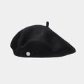 Close-up of a black wool beret featuring a silver metallic badge with engraved details - Black