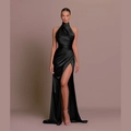 Elegant black halter satin maxi dress with side slit and waist pleats on warm background - Black