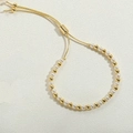 Macro detail of 14K gold plated bead bracelet with white pearls and adjustable slider clasp - 4mm