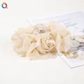 Close-up of a cream chiffon rose hair claw clip with satin petals and transparent teeth - Champagne