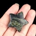 Star-shaped Kambaba Jasper carved stone with green circular patterns held in hand - Rhyolite