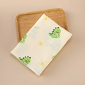 Close-up of soft double-layer muslin baby swaddle with green dinosaur and sun prints - 100x100cm / Small Dinosaur
