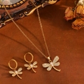 Set di gioielli con libellula dorata, perle e cristalli in un ambiente da studio vintage - Set Libellula in Zirconia Bianca Dorata (T031)