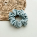 Detail of ice blue satin scrunchie showing glossy silk texture and elegant folds - Medium Light Blue
