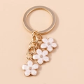 Golden cherry blossom keychain with three white enamel sakura pendants on pink background - White