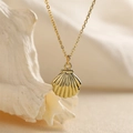 Close-up of a golden seashell pendant necklace with detailed texture on a soft background - Solid Metal Texture Style / Gold