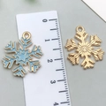 Blue enamel snowflake charm with gold plating and reverse side shown next to a ruler - Lake Blue Snowflake 18x22mm