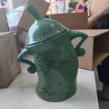 Detailed view of green ceramic canister with red spots, unique hands-on-hips shape and lid - Green
