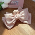 Dettaglio di una pinza per capelli in raso rosa con grande fiocco su tavolo di legno - Fermaglio a fiocco bifacciale / Rosa