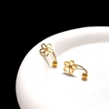 Macro shot of gold floral earrings with curved pins and ball backs on a curved edge - Gold Hollow Flower U-Shape Ear Cuff (Single)