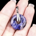 Blue purple natural stone donut pendant with silver metal buckle held by fingers - 20mm Sodalite