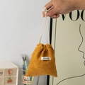 Handheld view of a large yellow corduroy drawstring pouch with white woven label detail - Ginger Yellow