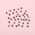 DIY black flower-shaped clay beads for handmade bracelets on a pink background - Black