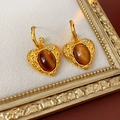 Detail van vintage hart oorbellen met bruine hars en kristal op een beige tableau - Zilveren Pin Goudkleurig Koffiebruin (S925 Zilveren Pin)