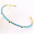 Detail of gold open bangle featuring light blue enamel stripes and black dot accents - Sky Blue