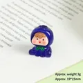 Macro shot of a mini resin cartoon figure in blue hoodie on an open book, size 19x15mm - Luminous Blueberry