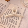 Matte cream large shark hair claw clip on an open book with elegant soft lighting - 11cm / Matte Cream