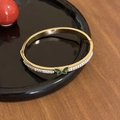 Detailansicht eines vergoldeten Armreifs mit weißen Zirkonia und grünem Schmetterlingsanhänger - Gold - Grüner Schmetterling