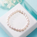 Detail of white oval freshwater pearl elastic bracelet on a textured white gift box - 5-6mm Rice Shape Pearl / White