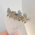 Barrette papillon dorée avec strass bleus et transparents sur carte de luxe - Style Trois Papillons