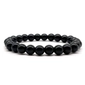 Macro shot of 8mm polished black agate beads on an elastic stretch bracelet string - Black Glass