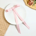 Détail d'un nœud papillon en satin rose avec de longs rubans sur une assiette - Rose